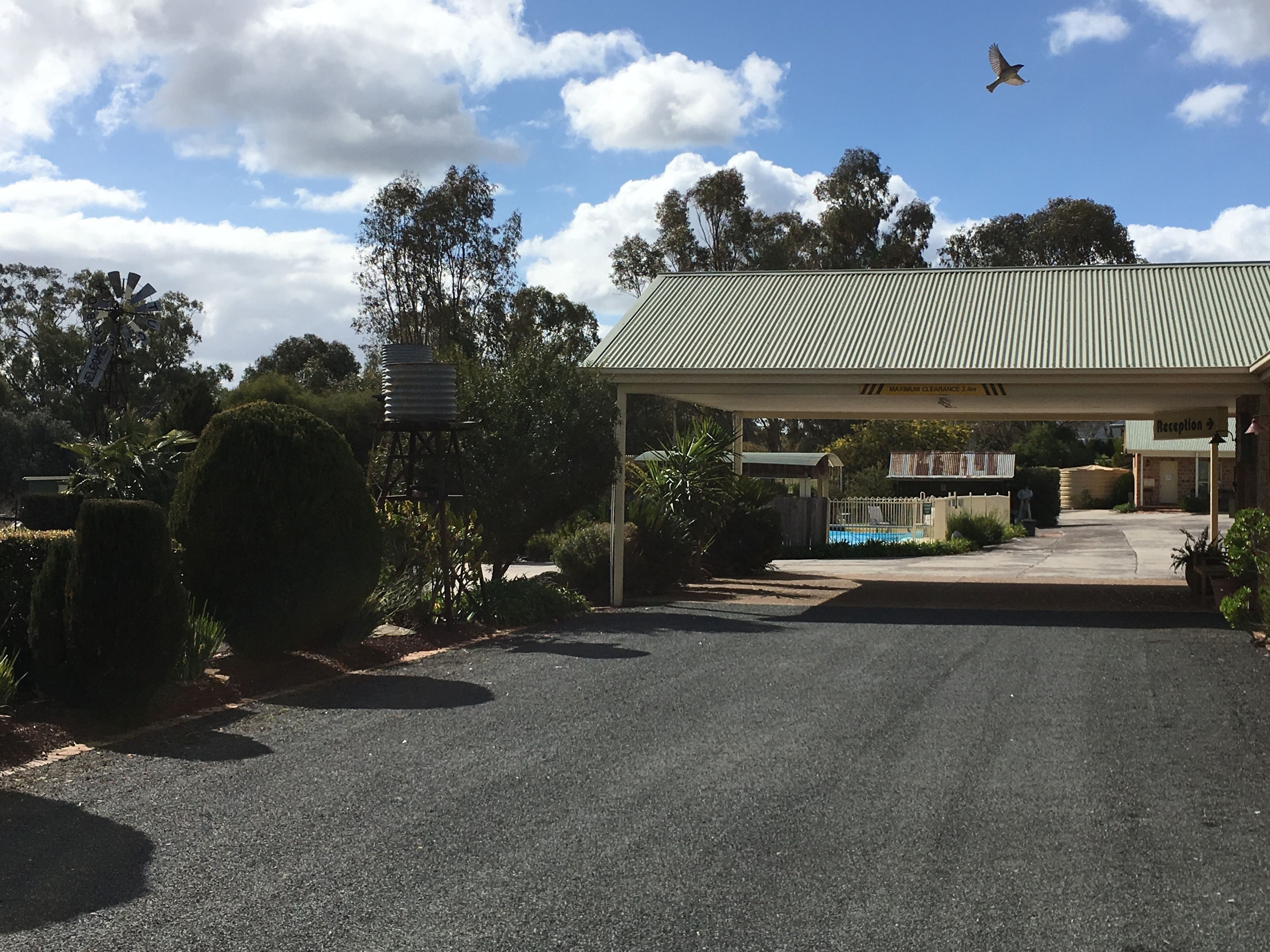 A building with a corrugated metal roof, a covered entrance, and a pool area visible in the background.