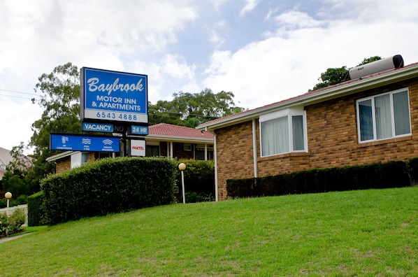 A Baybrook Motor Inn & Apartments with a signboard indicating a vacancy and contact number.