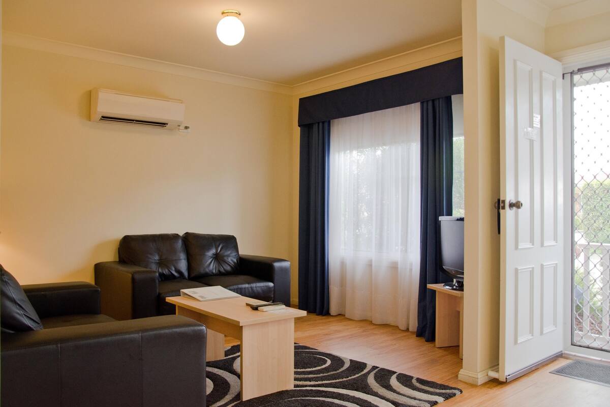 A living room with a sofa, a coffee table, and a television on a stand.