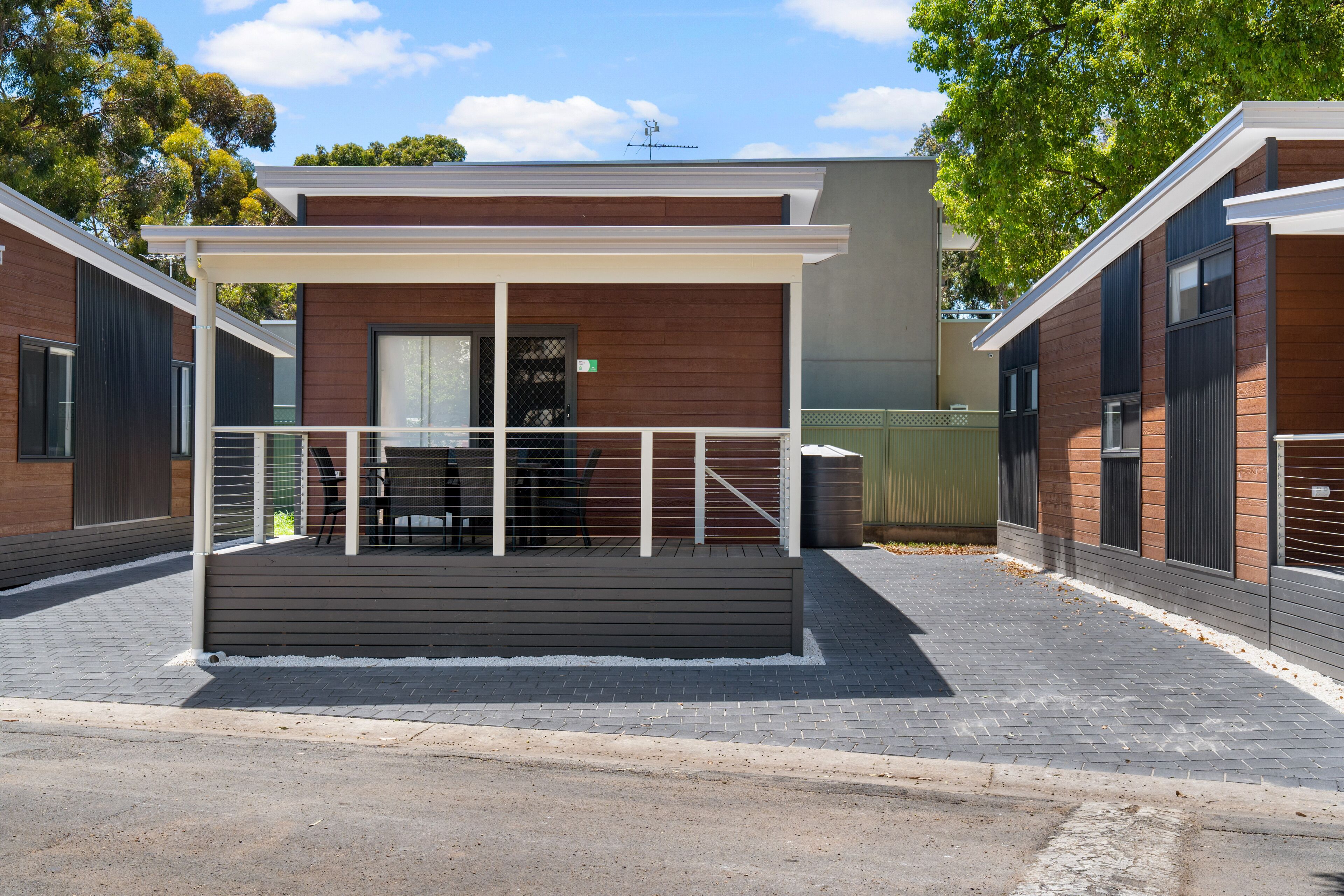 A modern building with a covered outdoor seating area, a gated entrance, and a paved walkway.