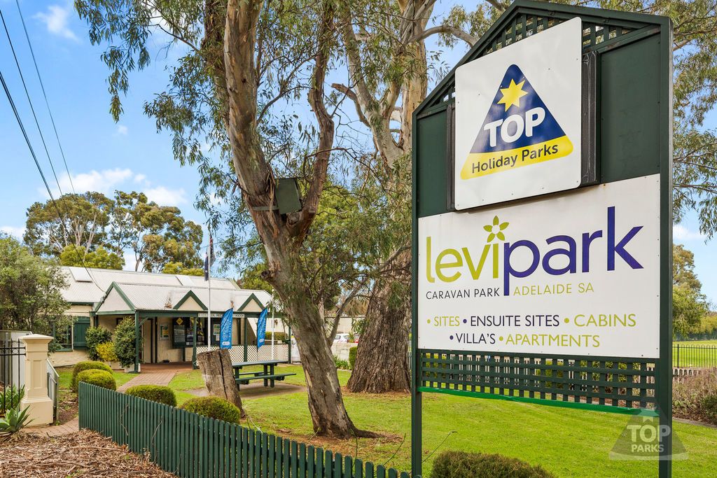 A sign for Levitpark, a caravan park in Adelaide, SA, with amenities like sites, en-suite sites, cabins, villas, and apartments.