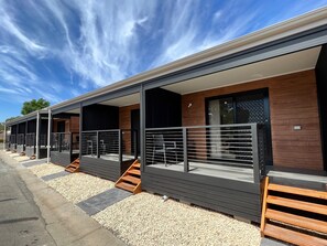 A modern hotel with a covered outdoor area, wooden steps, and a gravel pathway. - Levi Adelaide Holiday Park (Vale Park)