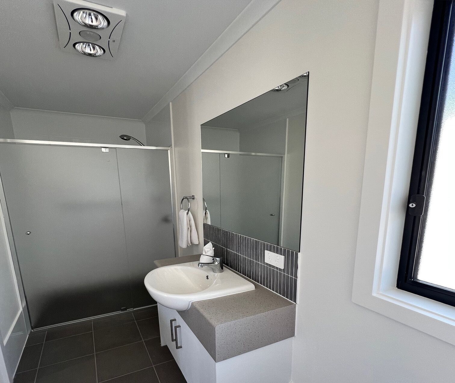 A modern bathroom with a shower, a sink, and a large mirror.