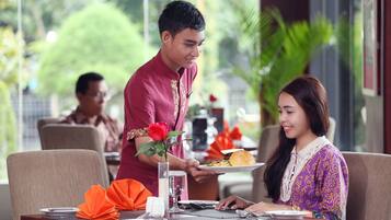 A restaurant setting with a waiter serving a plate of food to a seated couple.