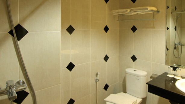 A bathroom with a toilet, sink, and shower. - Grand Hatika Hotel (Tanjung Pandan)