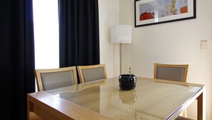 A conference room with a glass table, two wooden chairs, a black vase with a plant, a white floor lamp, and a framed painting on the wall. - Cape Jervis Holiday Units (Cape Jervis)