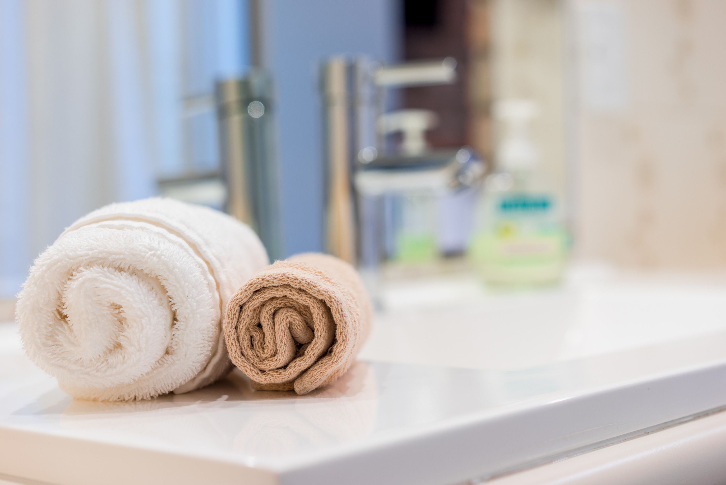 Two rolled towels on a bathroom counter.