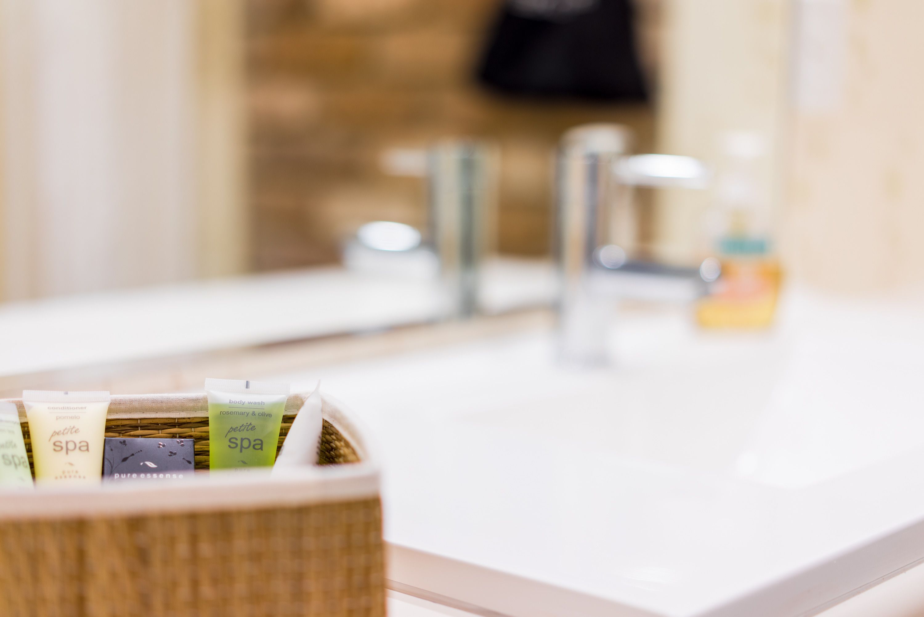 A bathroom with a sink, a mirror, and a wicker basket containing toiletries.