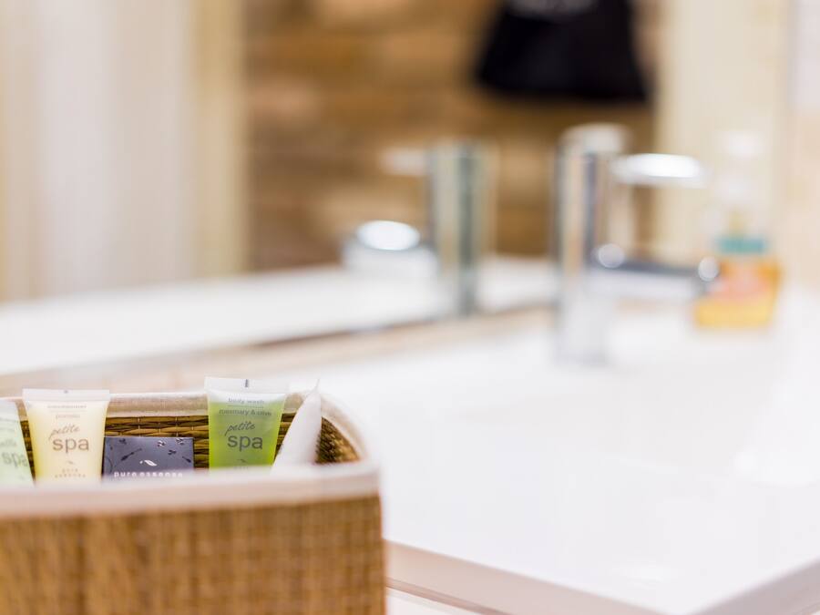 A bathroom with a sink, a mirror, and a wicker basket containing toiletries.