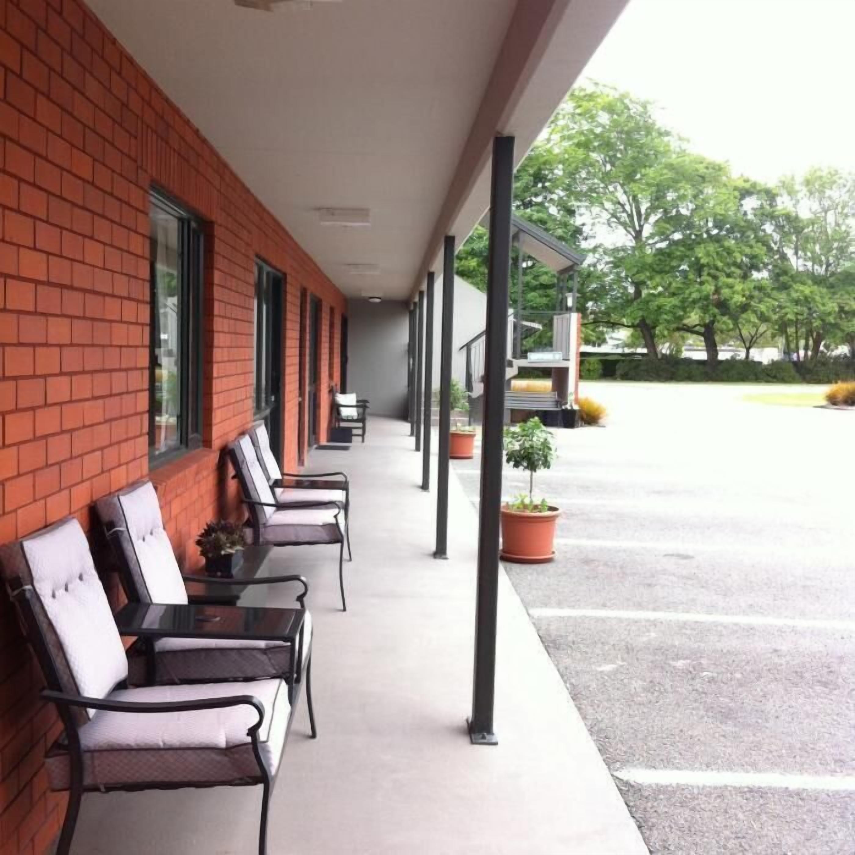 A covered outdoor seating area with brick walls and metal chairs.