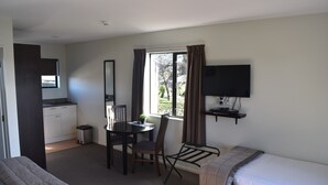 A hotel room with a bed, a desk with a chair, a television, and a window with curtains. - Darfield Motel (Darfield)