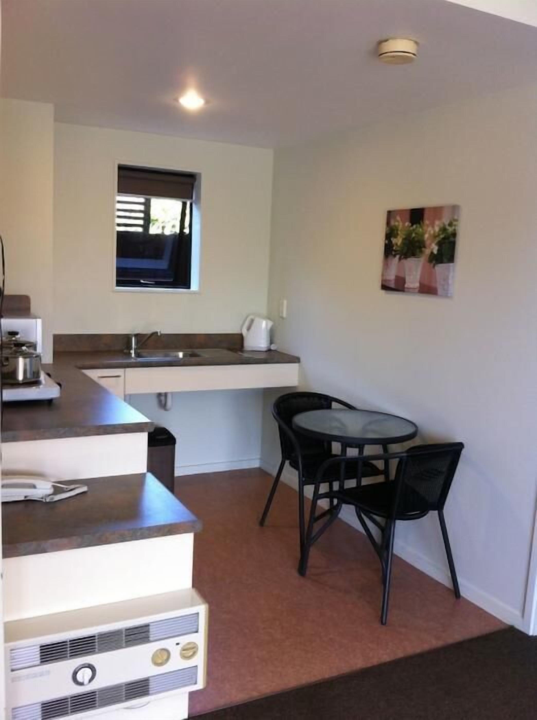 A compact kitchen with a sink, stove, and a small dining area with a table and chairs.