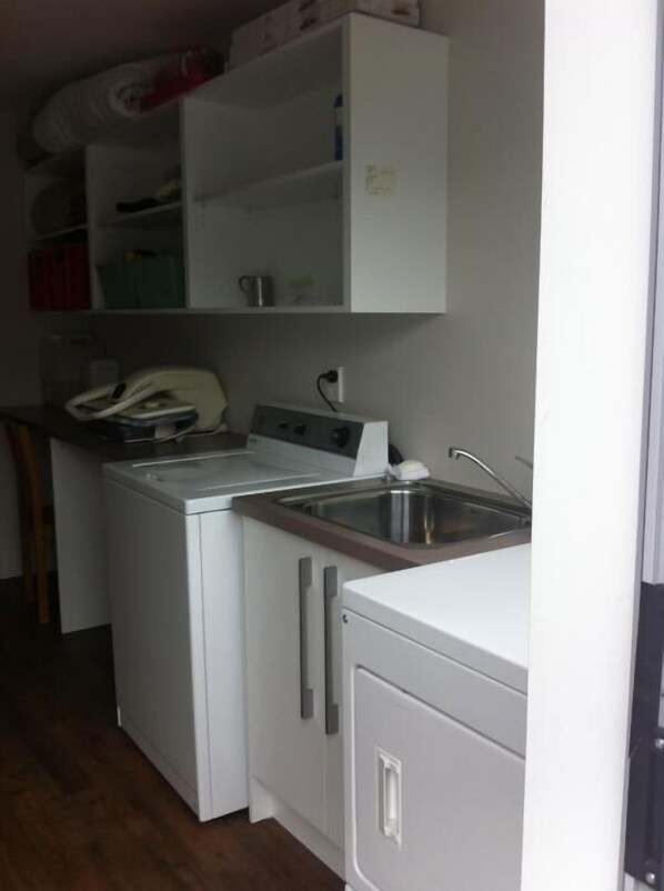 A compact kitchen with a washing machine, a small sink, and cabinets.
