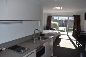 A modern kitchen with a built-in oven, a sink, and a countertop. There is a bed with a view of the outdoors.