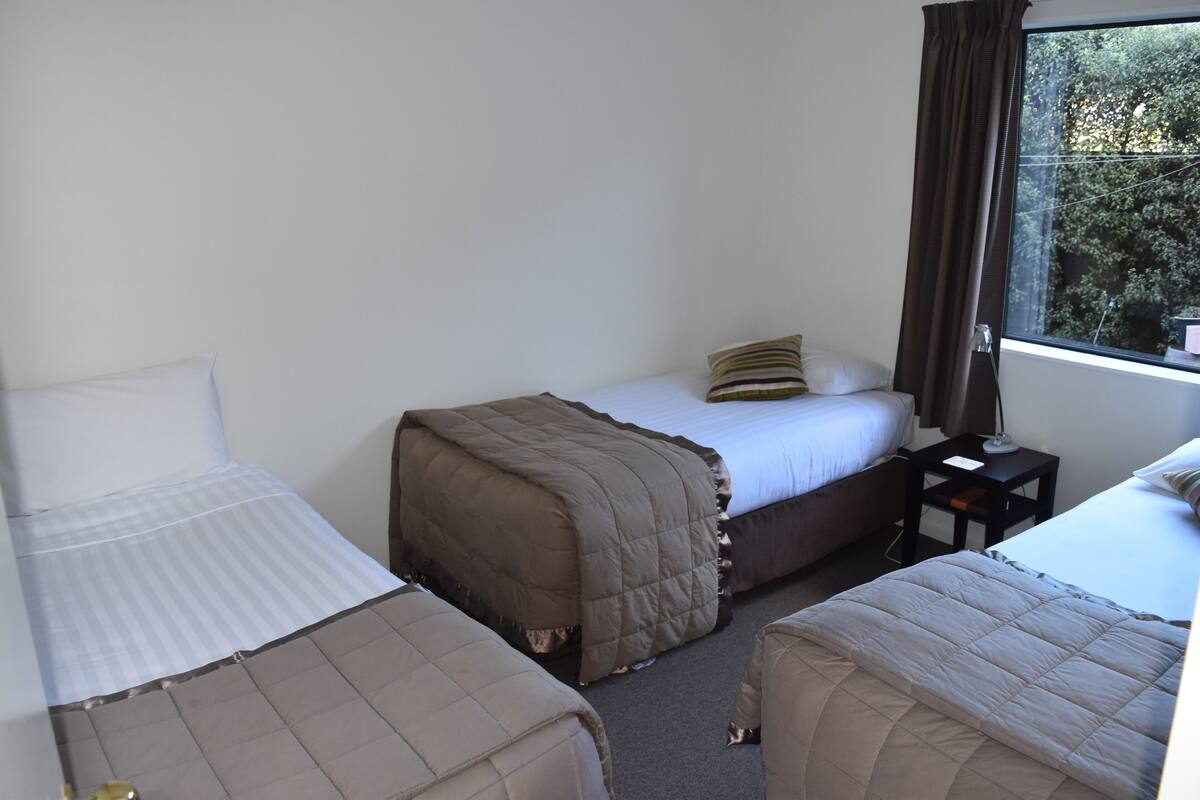 Una habitación de hotel con dos camas individuales, una mesita y una ventana con cortinas.