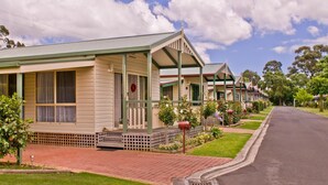 A row of traditional Australian cottages with verandas, a brick pathway, and a street view. - Warragul Gardens Holiday Park (Warragul)