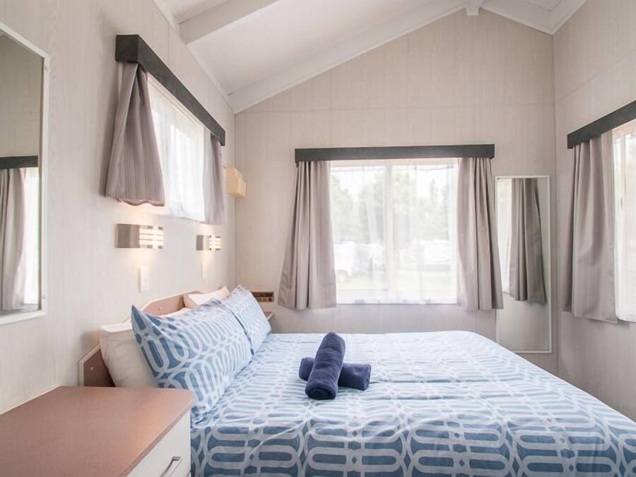 Ein Schlafzimmer mit einem großen Bett, einem Nachttisch und einem Fenster mit Vorhängen.