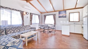 A spacious living area with a sofa, dining table, and kitchen area. - Warragul Gardens Holiday Park (Warragul)