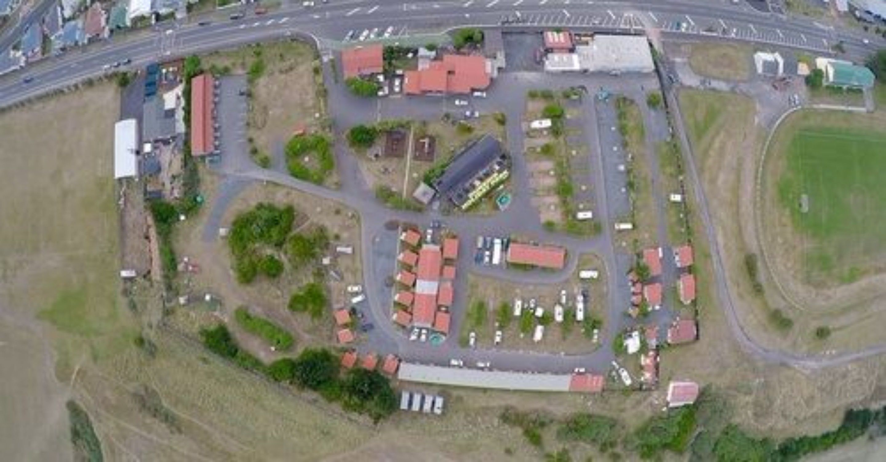 An aerial view of a commercial area with multiple buildings, parking lots, and a road.