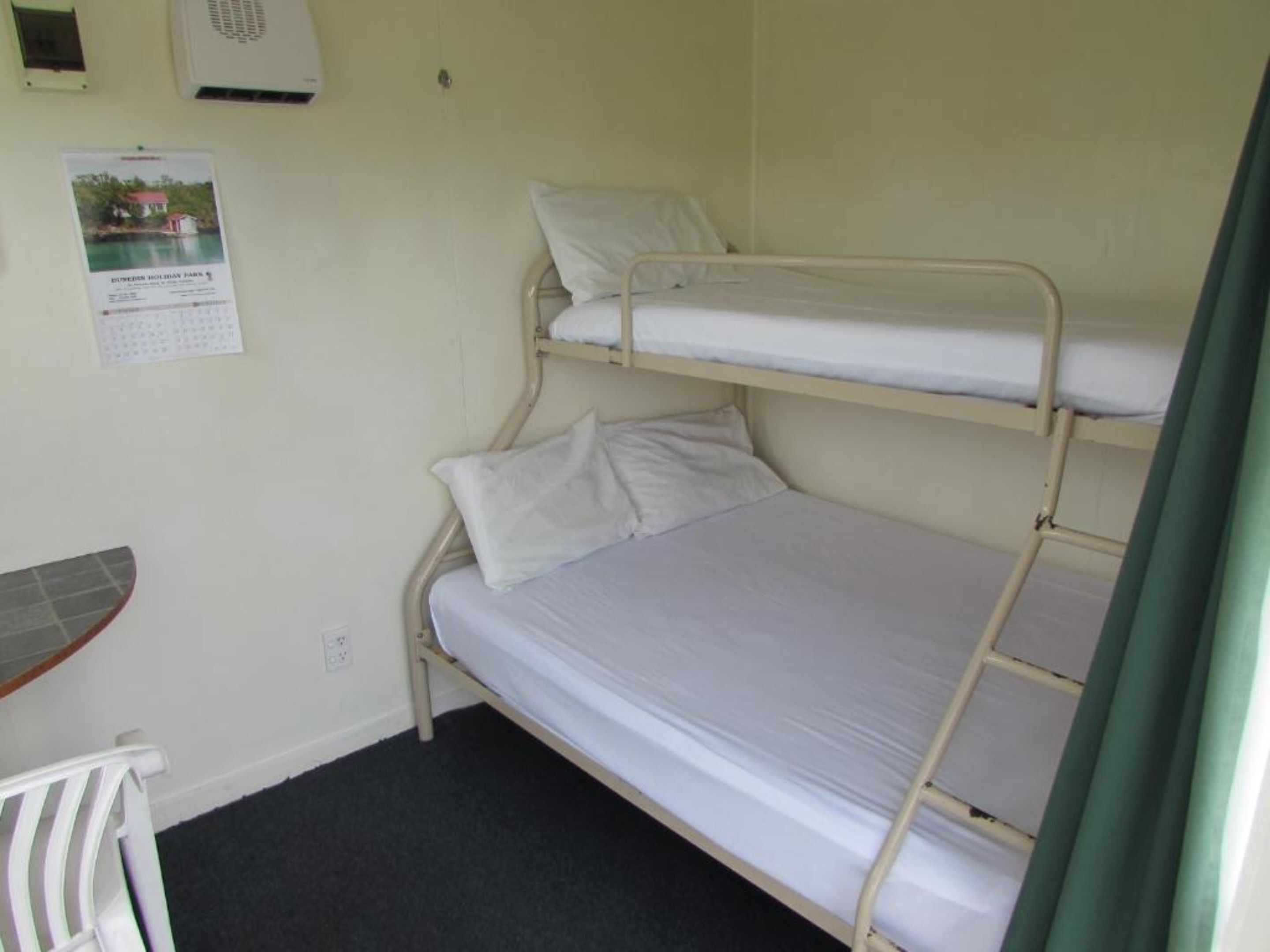 A bunk bed room with a small table and a poster on the wall.