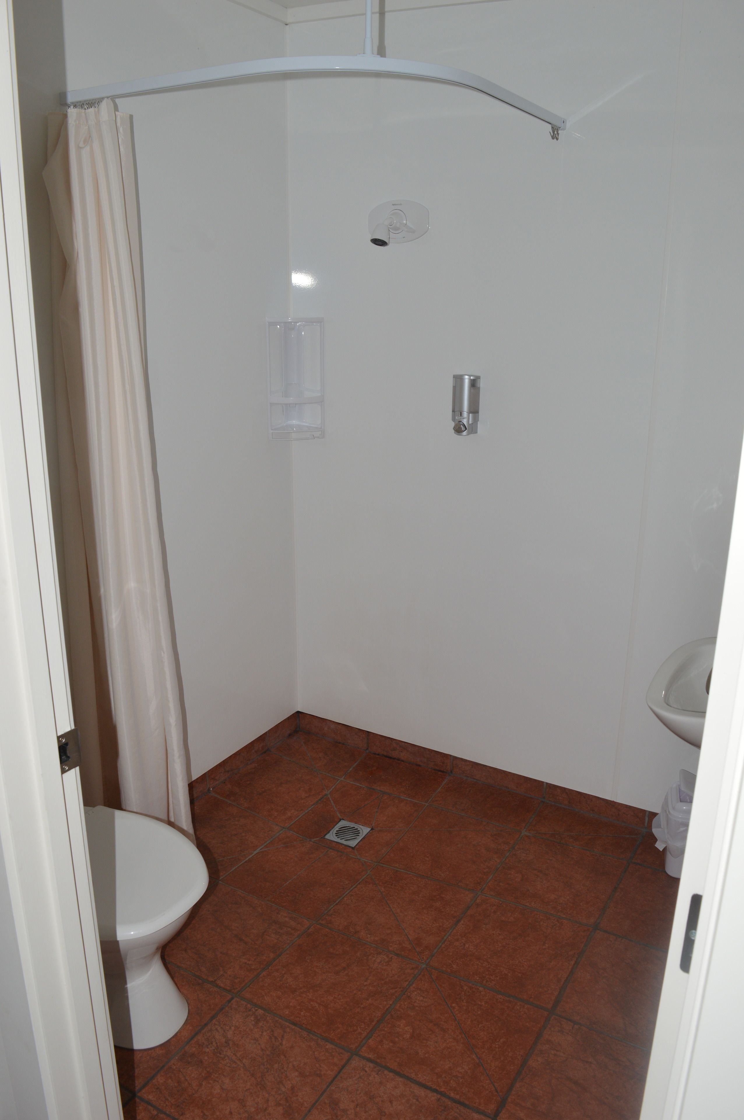 A small, compact bathroom with a shower, toilet, and sink.