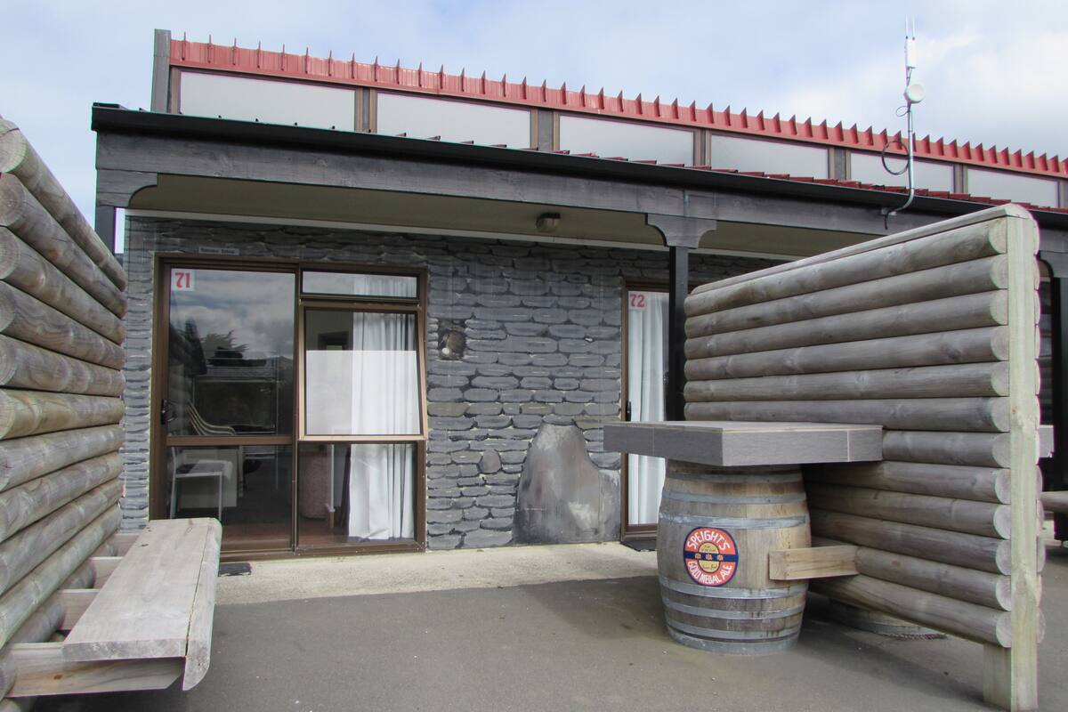 A building with a stone facade, a wooden door, and a large barrel labeled "Speights Good Medal Ale".