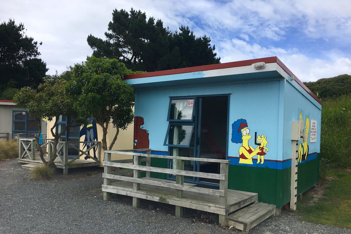 A small building with a blue and white exterior, a wooden deck, and a mural of two cartoon characters.