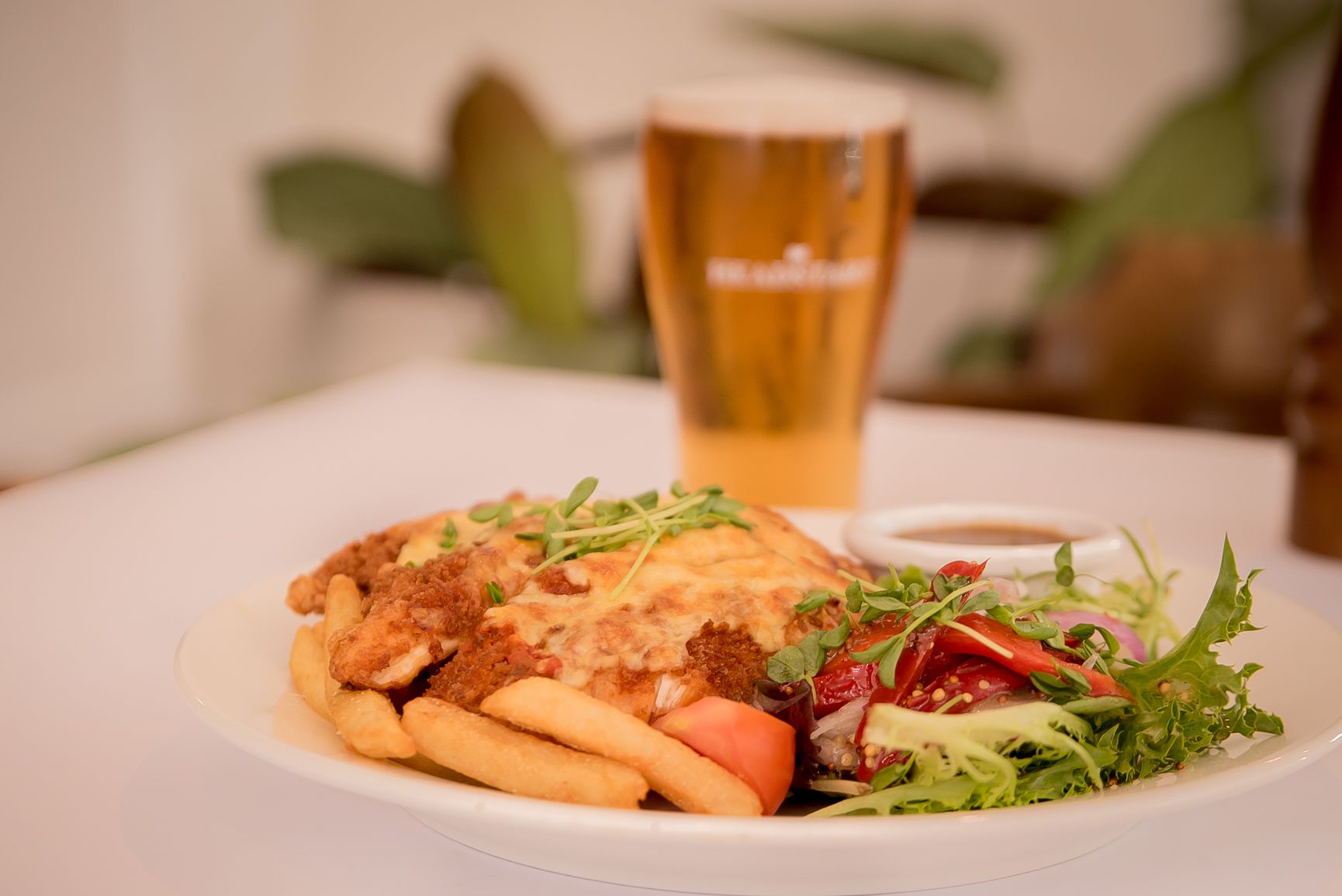 A plate of food with fries, a salad, and a beer glass.
