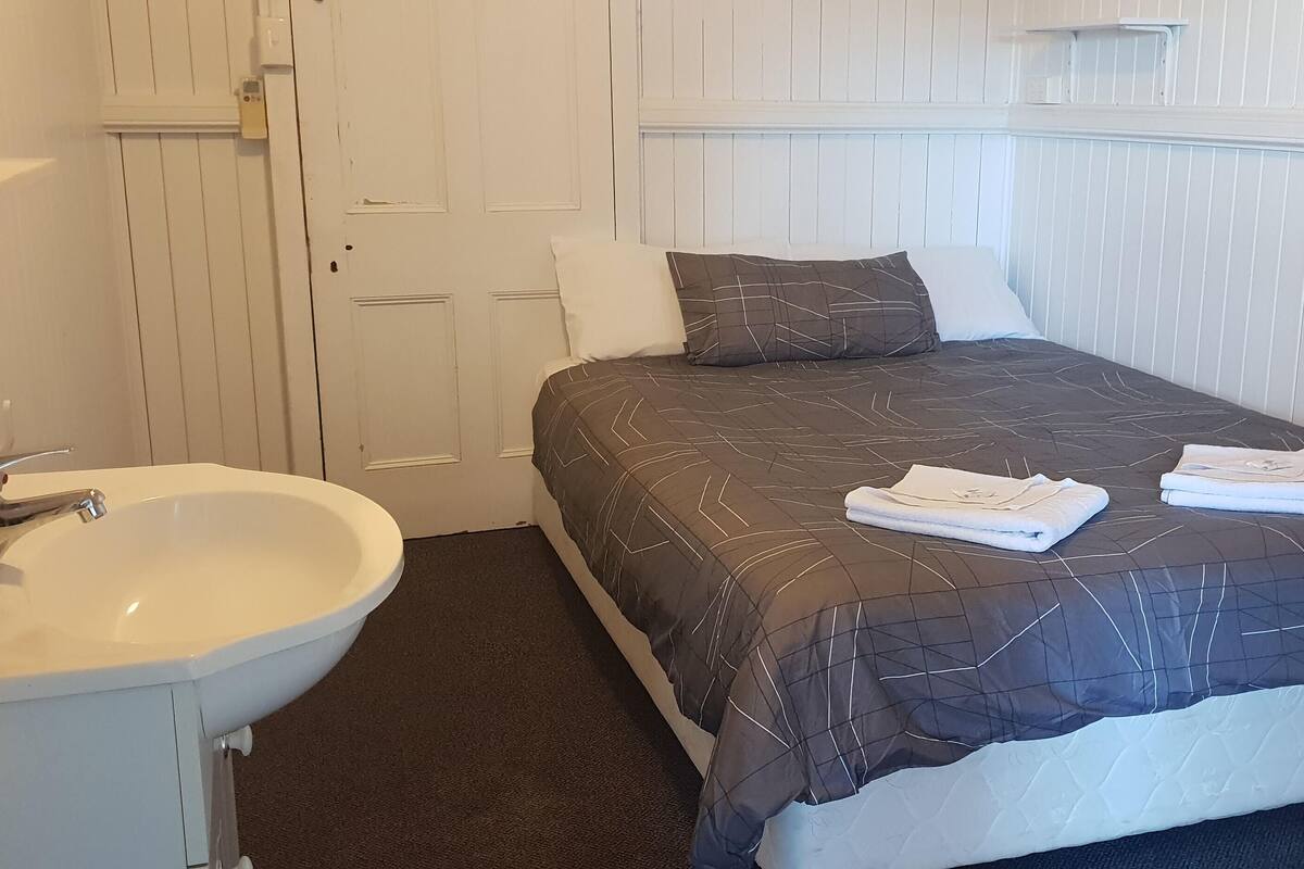 A hotel room with a bed, a white sink, and a door.