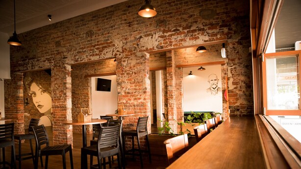 A restaurant with brick walls, wooden tables, and chairs. - Queens Arms Hotel (Roma)