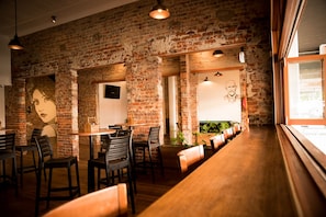 A restaurant with brick walls, wooden tables, and chairs. - Queens Arms Hotel (Roma)