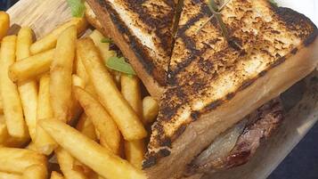 Una bandeja de madera con sándwiches a la parrilla y papas fritas.