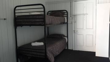Quarto com beliche, porta branca e radiador.
