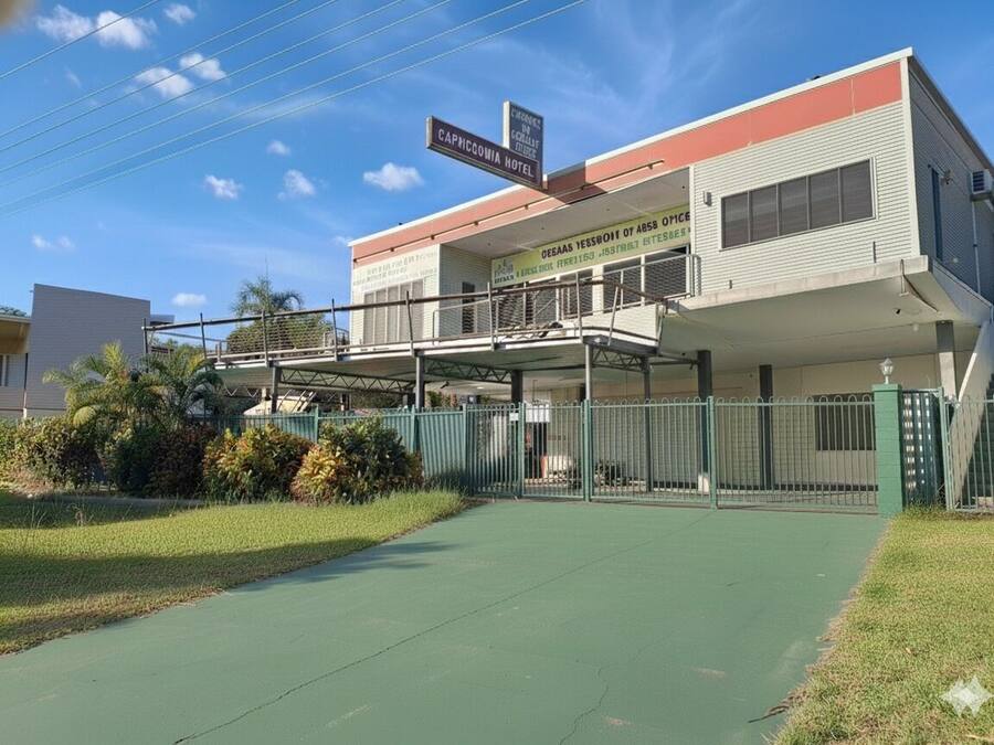 A hotel with a flat roof, a covered walkway, and a fenced parking area.