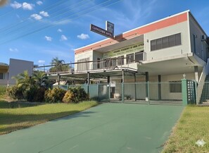 Un hotel con techo plano, una galería techada y un estacionamiento cercado.
