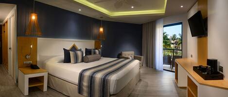 A modern hotel room with a large bed, bedside tables, a TV, and a balcony with a view.