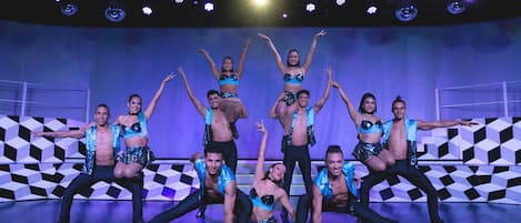 A dance performance on a stage with geometric patterned walls and a central spotlight.