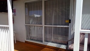 A screened porch with a white railing, a bench, and a view of a house through the window. - Admirals Lodge Picton (Picton)