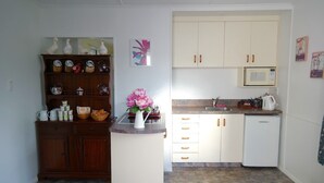 A compact kitchen with wooden cabinets, a central island, and a microwave. - Admirals Lodge Picton (Picton)