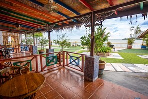 An outdoor patio with tiled flooring, wooden furniture, and potted plants. - Lost Paradise Resort (George Town)