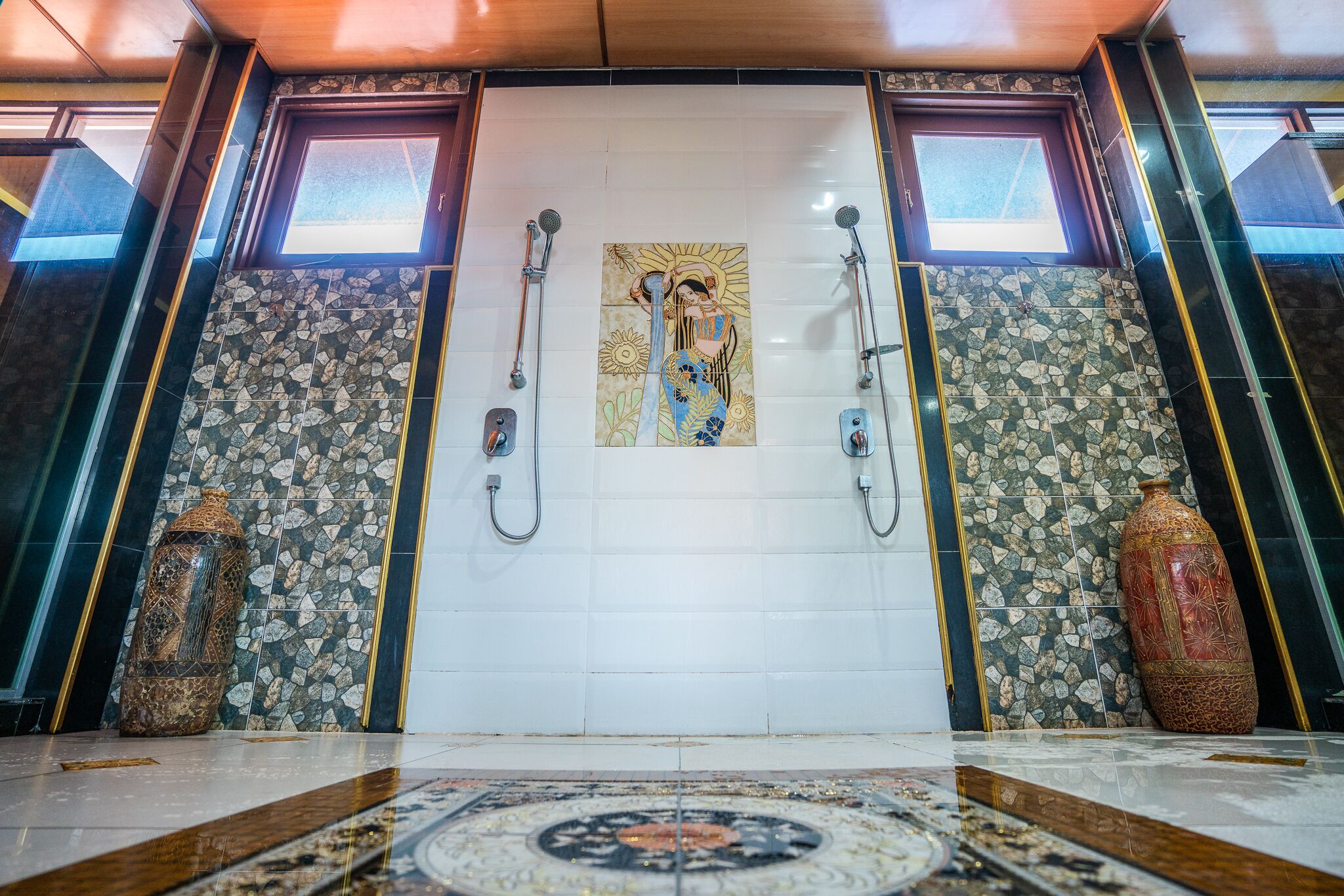 Een badkamer met een betegelde wand, een grote vaas en een decoratief tegeltapijt op de vloer.