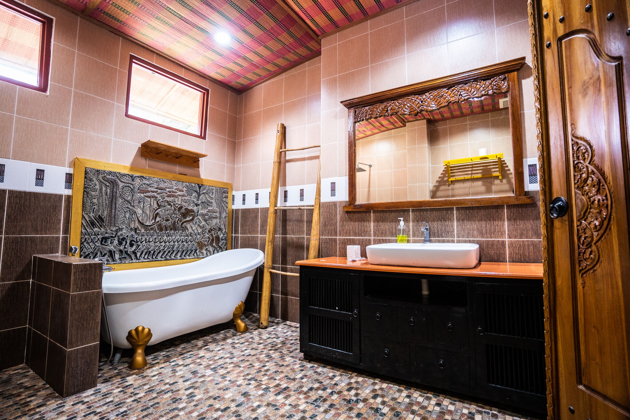 A bathroom with a bathtub, a wooden vanity with a sink, a mirror, and a tiled floor.