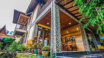 A multi-story building with a balcony, outdoor seating area, and potted plants.