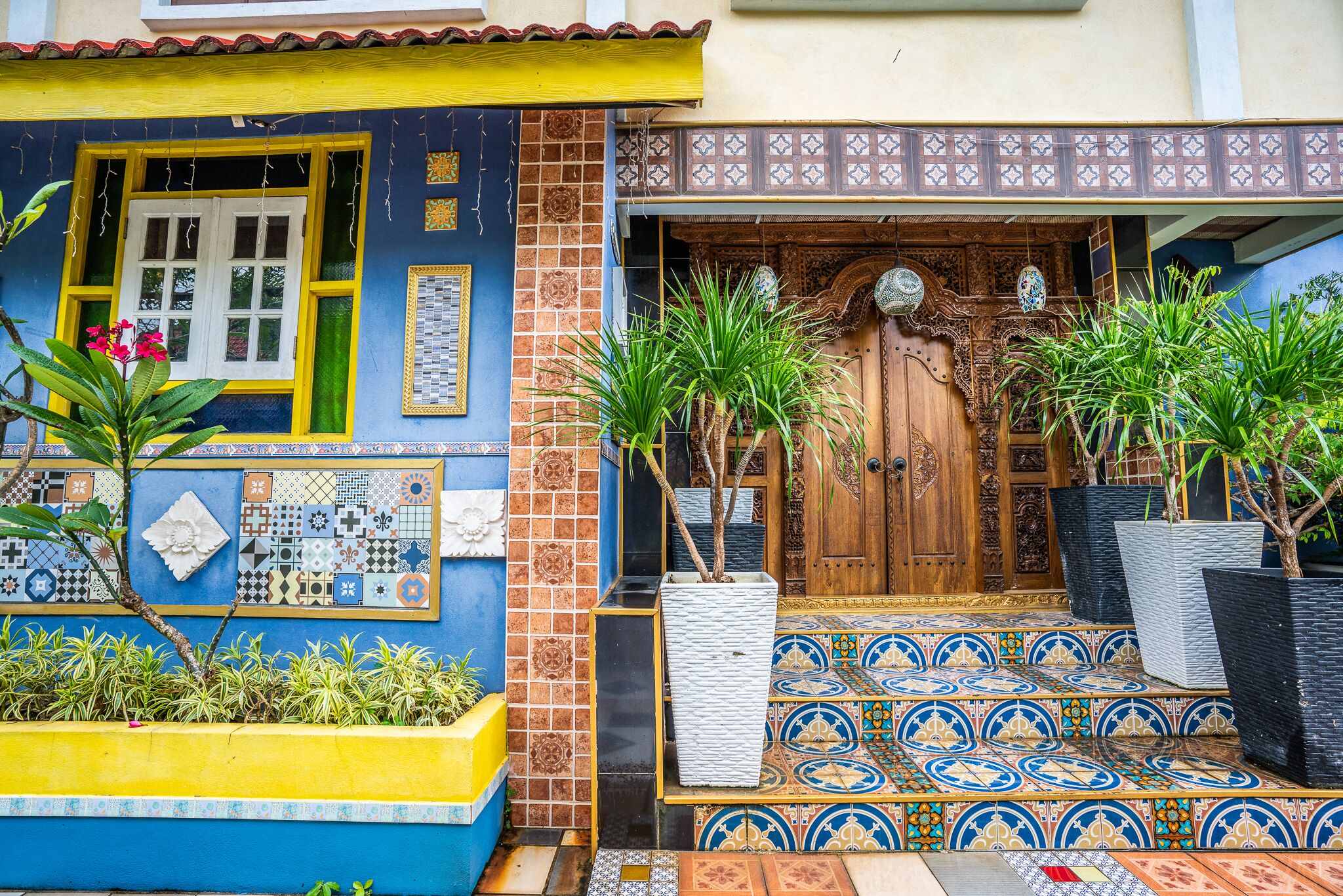 A colorful building with a tiled entrance, potted plants, and a decorative door.