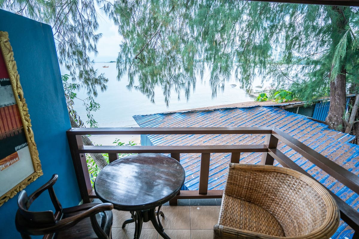 Ein Balkon mit Blick auf ein Gewässer, einem Tisch und zwei Korbstühlen.
