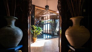 Una puerta que da a una habitación con jarrones grandes a cada lado y una planta en maceta en el centro.