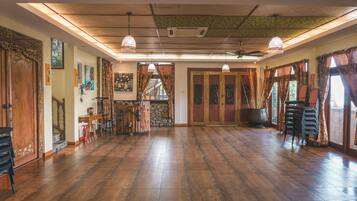 A spacious room with wooden flooring, a staircase, and a bar area.