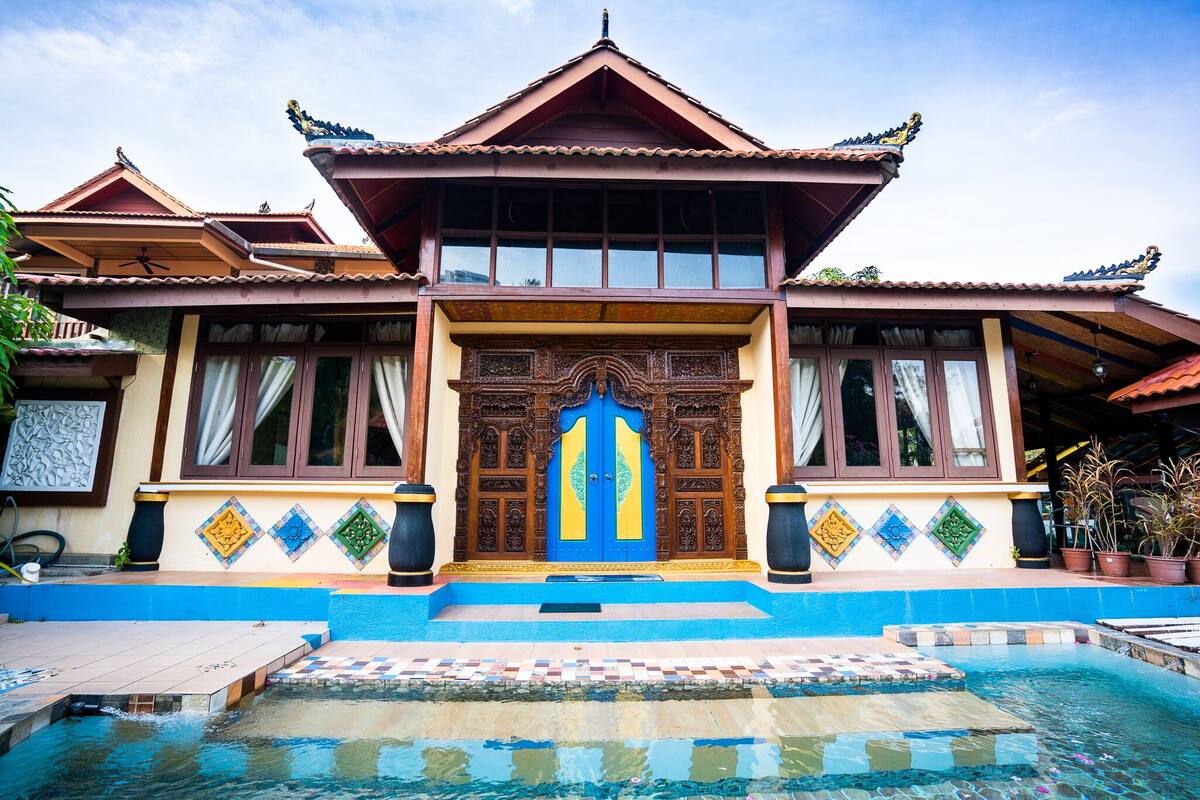 Ein traditionelles Gebäude mit einem markanten Eingangsbereich, einem mit Fliesen ausgelegten Pool und dekorativen Elementen.
