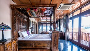 Una cama con dosel de madera y cortinas, una ventana grande y vistas al exterior.