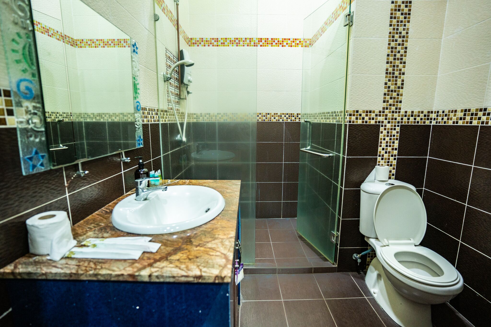 A bathroom with a marble sink, a toilet, and a glass shower enclosure.